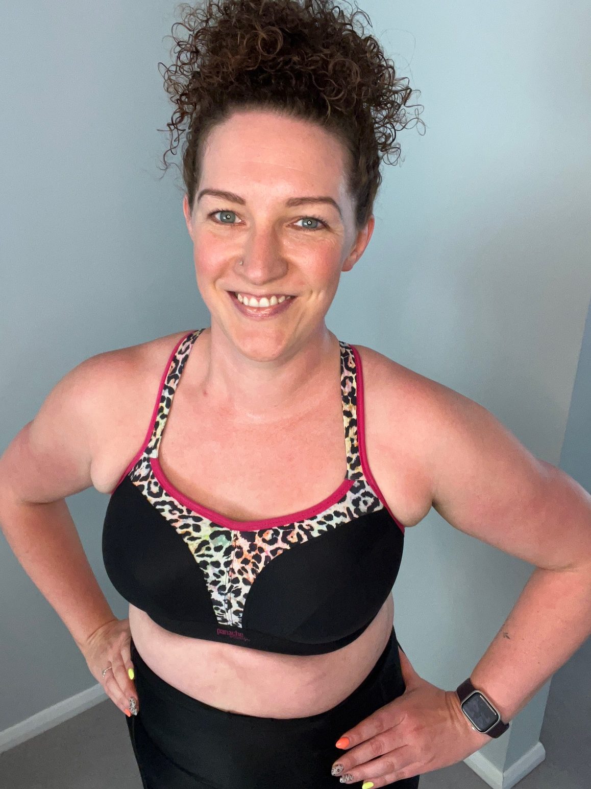 Woman poses in black sports bra with colourful leopard print trim