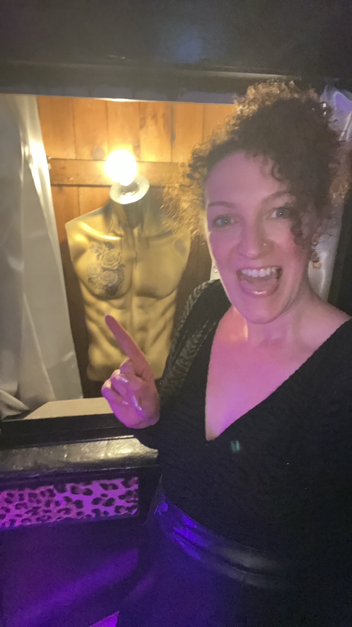 Becky Hughes stands pointing to a lamp made from the torso of a mannequin