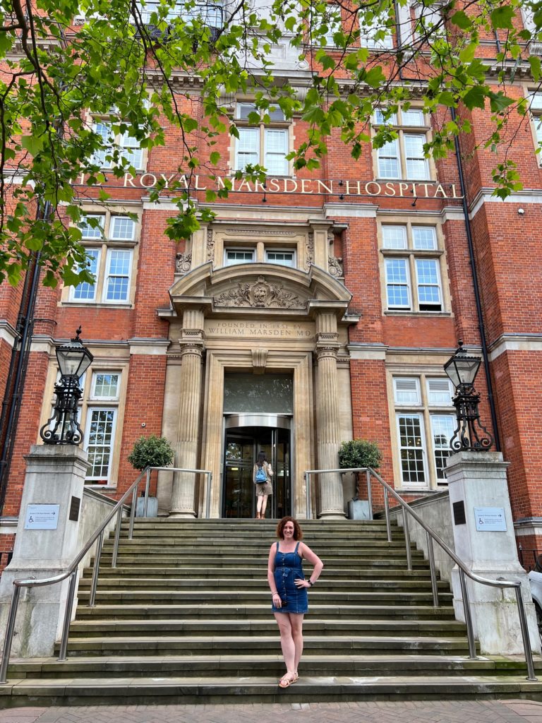 Woman in short denim dress poses on the steps outside the main entrance to the Royal Marsden hospital, Chelsea